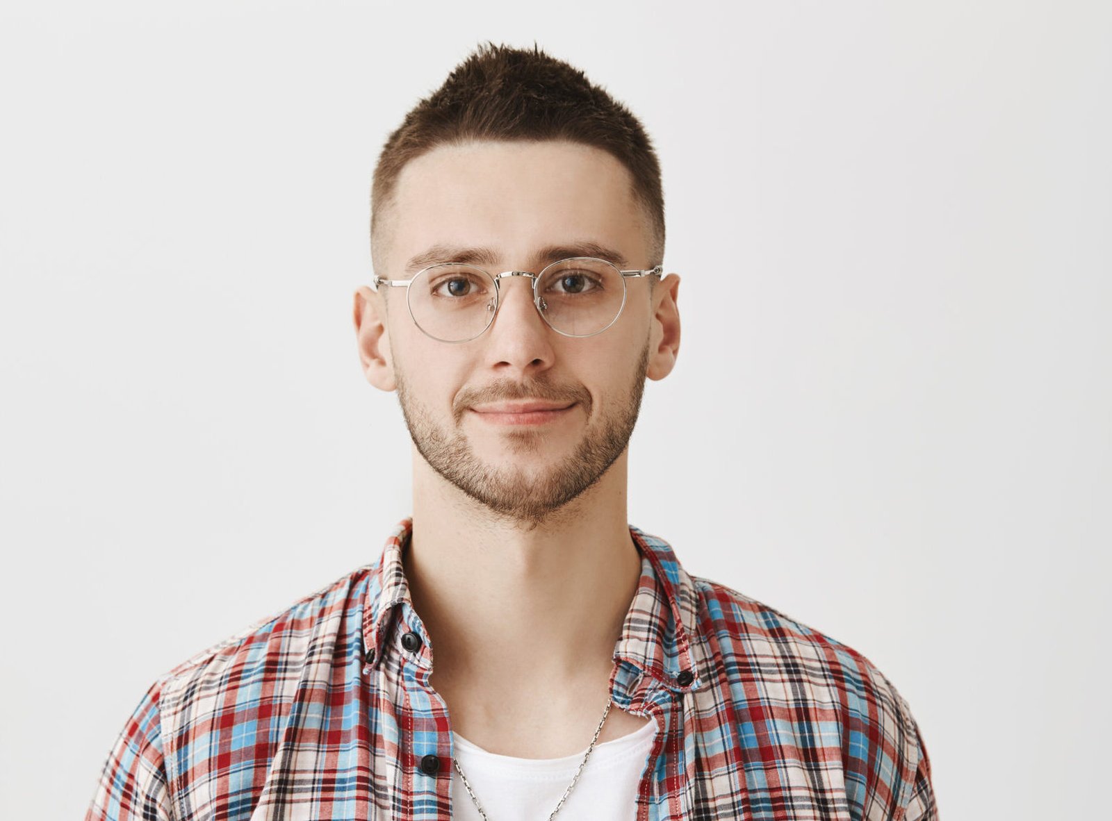 Waist-up portrait of calm and successful young businessman, wearing glasses and smiling at camera. Young entrepreneur listens to customers complaints. Office worker on meeting with boss. Emotions concept